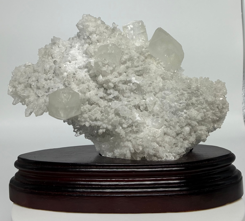 Calcite and Quartz crystal cluster on a wooden stand against a white background